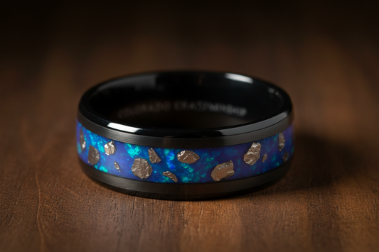 Black ceramic custom wedding ring with blue opals on a wood background