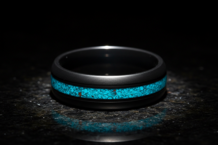Handcrafted matte black tungsten memorial ring with turquoise channel inlay on polished black granite — WildBeard Legacy Co.
