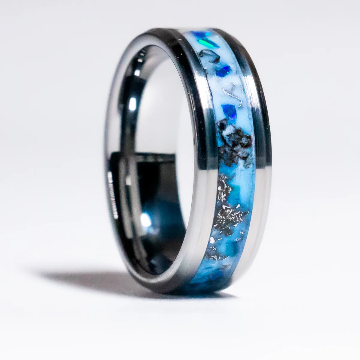 Silver ring with blue and black inlay on a white background