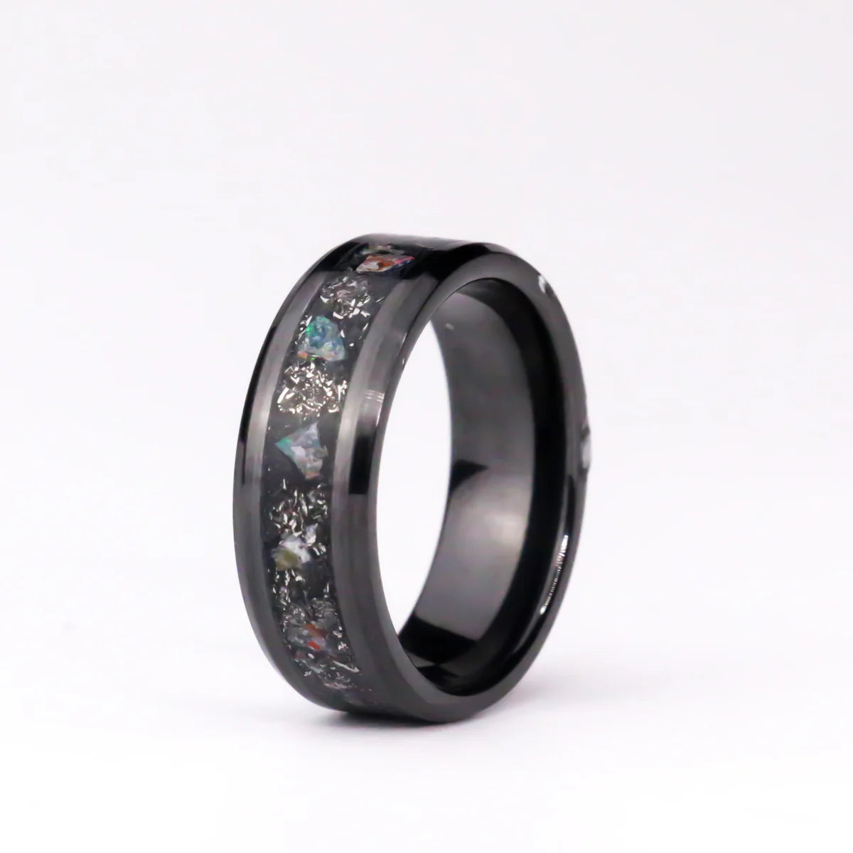 Black ceramic ring with embedded colorful stones on a white background