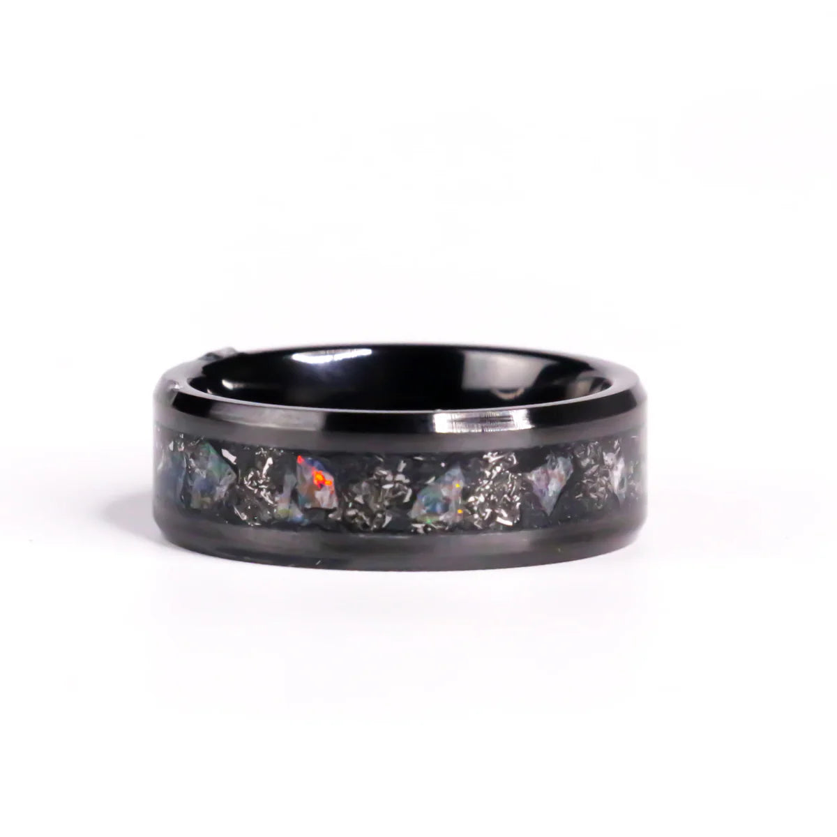 Black ceramic ring with embedded stones and shaved metal on a white background